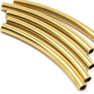 May include: A set of six gold-colored metal tubes, each with a rounded end. The tubes are arranged in a semi-circle, with the ends of the tubes facing the viewer.