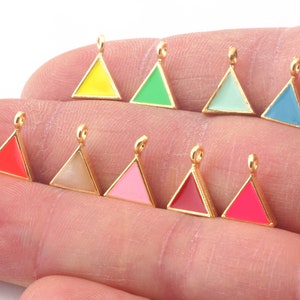 Puede incluir: Surtido de diez dijes triangulares de tono dorado con revestimiento de esmalte en varios colores, incluidos rojo, rosa, amarillo, verde, azul y blanco.