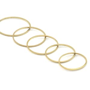 Op de afbeelding: Set van zes gouden metalen ringen in verschillende maten, gerangschikt in een aflopend patroon.