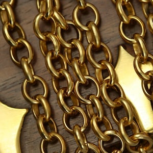 May include: Close-up of multiple gold chains with a star-shaped pendant. The chains are interlocked and have a shiny, metallic finish.