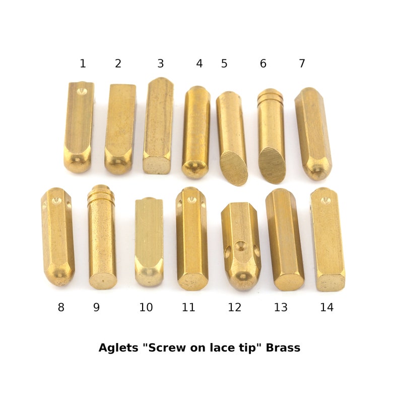 May include: Fourteen brass aglets, or screw-on lace tips, in various shapes and sizes. The aglets are arranged in two rows of seven, numbered 1 through 14.
