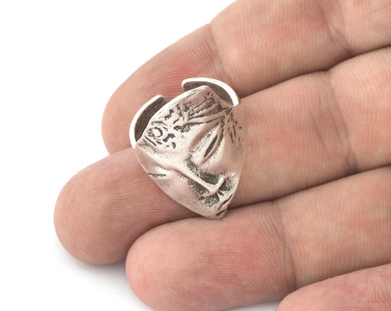 Peut inclure: Une bague en argent avec un design d&eacute;taill&eacute;, ressemblant &agrave; un visage ou un masque stylis&eacute;. La bague est ouverte d'un c&ocirc;t&eacute;, ce qui sugg&egrave;re qu'elle est ajustable.
