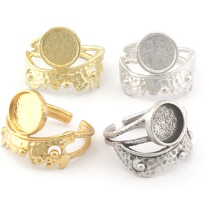 May include: Four adjustable rings with a round bezel setting. Two rings are gold-toned and two rings are silver-toned. The rings are designed with a textured, ornate band.
