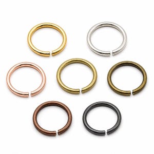 Pode incluir: Uma coleção de sete argolas abertas em vários acabamentos metálicos, incluindo dourado, prateado, ouro rosa, latão, bronze e preto. Estas argolas são projetadas com uma pequena abertura para fácil fixação a outros componentes de joalharia. Medidas em centímetros.