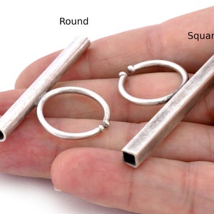 May include: Two silver metal rings, one round and one square, with a silver metal bar attached to each. The bar with the round ring is labeled "Round" and the bar with the square ring is labeled "Square".