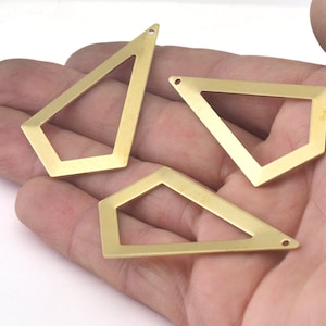 May include: Three gold-colored metal geometric shapes with open centers. The shapes are in the form of irregular pentagons with rounded corners. Each shape has a small hole at the top.