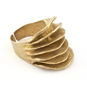 以下が含まれることがあります： 複数の重なり合った、テクスチャ加工が施された、わずかに湾曲したバンドを特徴とする、ユニークなデザインのゴールドトーンのリングです。