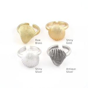 May include: Four adjustable rings with a seashell design in different finishes: raw brass, shiny gold, shiny silver, and antique silver.