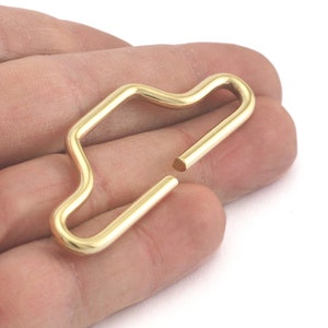 May include: A gold-colored metal key ring with a unique, wavy, open design. The ring is made of a single piece of metal and is designed to be durable and long-lasting.