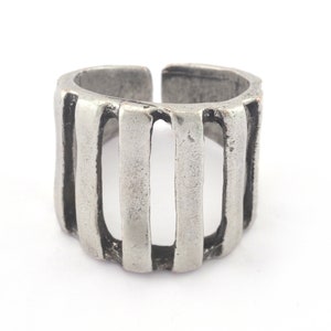 Puede incluir: Un anillo de plata con un diseño de barra vertical. El anillo está hecho de metal y tiene un acabado rústico.