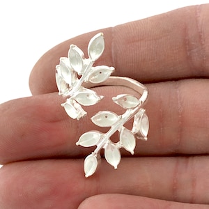Puede incluir: Anillo de plata con un delicado diseño de hojas. El anillo es abierto y ajustable para adaptarse a diferentes tamaños de dedos.