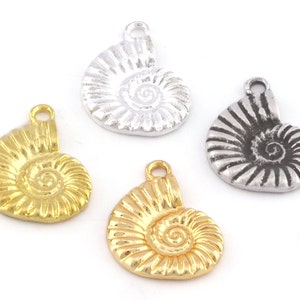 Puede incluir: Tres abalorios de concha de amonita en oro y plata. Los abalorios están detallados con líneas en relieve y un diseño en espiral. Los abalorios son perfectos para la elaboración de joyas o manualidades.