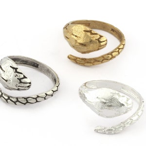 May include: Three silver and gold snake rings. The rings are designed to look like a snake wrapping around a finger. The snake's head is on the top of the finger and the tail wraps around the finger.