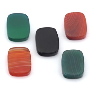May include: Five agate cabochons in various colours, including green, red, and black. The cabochons are all rectangular in shape and have a smooth, polished surface.