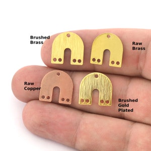May include: Four metal arch-shaped charms in different finishes: brushed brass, raw brass, raw copper, and brushed gold plated.