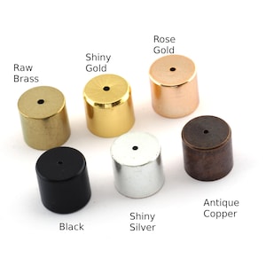 Op de afbeelding: Assortiment van ronde metalen flessenstoppers in verschillende afwerkingen, waaronder ruw messing, glanzend goud, rosé goud, antiek koper, glanzend zilver en zwart.