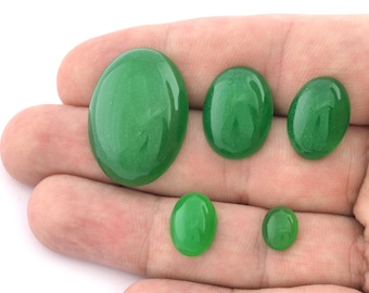 May include: Five oval-shaped green gemstones of varying sizes, displayed on a hand.