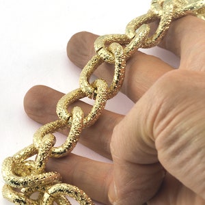 May include: A gold chain bracelet with a textured, chunky link design.