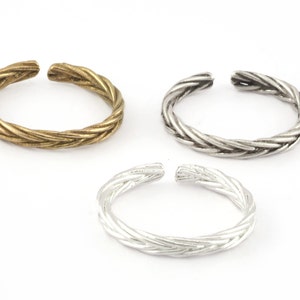 Peut inclure: Trois anneaux de pied tressés en or, argent et argent. Les anneaux sont faits d'un design en métal torsadé.