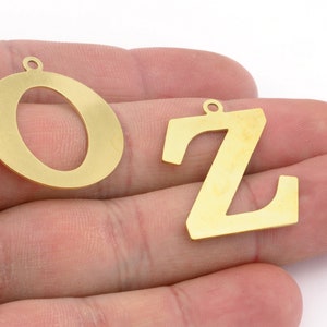 Può includere: Due ciondoli in metallo color oro, nello specifico le lettere O e Z. Ogni lettera presenta un piccolo occhiello circolare sulla parte superiore per l'aggancio. Le lettere hanno una superficie liscia e piatta con una finitura opaca.