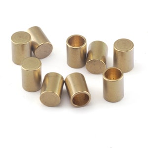 May include: A group of ten gold-coloured metal cylinder spacers. The spacers are arranged in a circle on a white background.