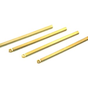 May include: Four gold-colored metal bars with rounded ends. The bars are of varying lengths and are arranged in a staggered pattern.