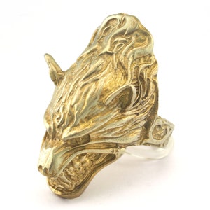 May include: A gold-toned ring featuring a detailed wolf head design. The wolf's head is facing to the left and has a fierce expression.