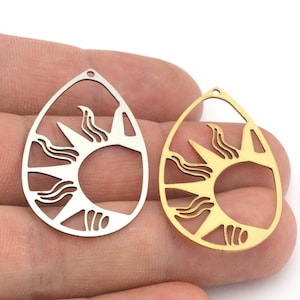 May include: Two metal sun pendant charms, one silver and one gold, with a cutout design of a sun with rays and waves. The charms are in the shape of a teardrop.