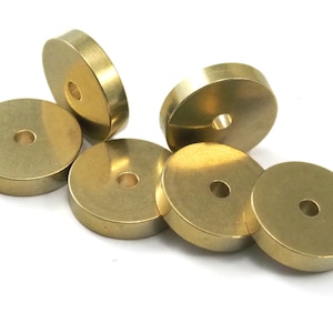 Könnte beinhalten: Sechs goldfarbene Metallscheiben mit einem Loch in der Mitte. Die Scheiben sind rund und haben eine glatte, polierte Oberfläche.