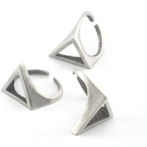 Puede incluir: Tres anillos de plata en forma de triángulo con un diseño geométrico. Los anillos son abiertos y ajustables.