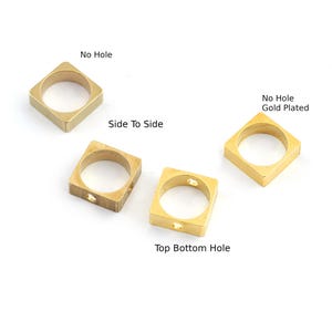 May include: Four square-shaped, gold-toned rings. Two rings have no holes, one is labelled "Side to Side", and the other is labelled "No Hole Gold Plated". The other two rings have holes labelled "Top Bottom Hole".