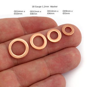 Pode incluir: Quatro arruelas de cobre de tamanhos variados são exibidas. A maior é rotulada OD14mm x ID10mm, e a menor é OD9mm x ID5mm. O texto "18 Gauge 1,2mm Washer" está no topo. As arruelas são circulares com um furo central.