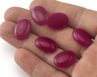 May include: Seven oval-shaped, deep pink gemstones. The gemstones are smooth and polished.