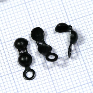 Op de afbeelding: Drie zwarte plastic toggle-sluitingen met een ronde vorm en een lus aan elk uiteinde.
