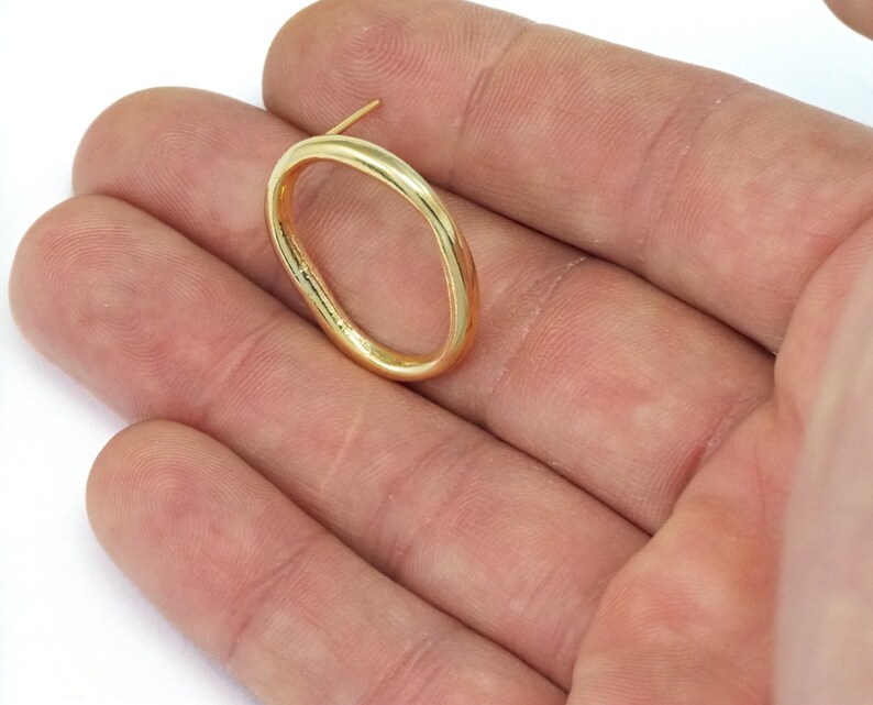 May include: A gold oval-shaped earring with a post.