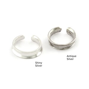 May include: Two silver ear cuffs, one with a shiny finish and the other with an antique finish. The ear cuffs are both simple and elegant.