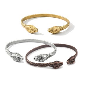 May include: A white ceramic mug with a black handle and the text "But First, Coffee" in a bold, black font. The mug is set against a blurred background, suggesting a cozy setting.