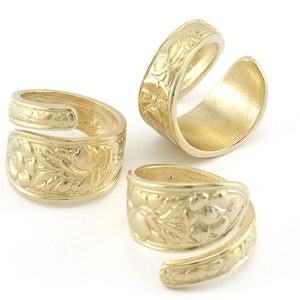 Pode incluir: Três anéis dourados com um design floral. Os anéis são abertos e podem ser ajustados para caber em diferentes tamanhos de dedos.