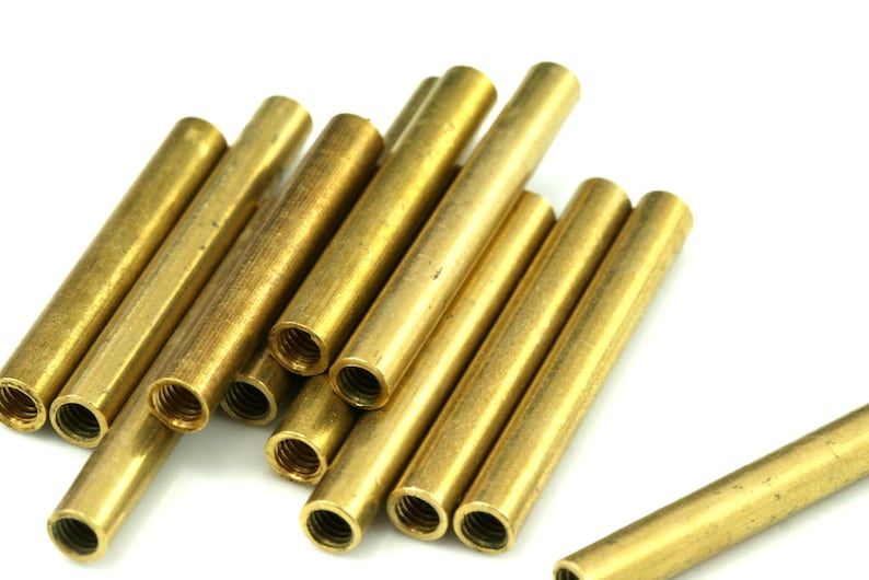 May include: A group of 10 gold-colored metal tubes with threaded ends. The tubes are arranged in a pile, with some overlapping.