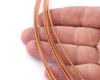 May include: Close-up of five strands of copper wire, each with a twisted, rope-like texture. The wire is a warm, reddish-brown color.