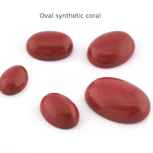Può includere: Cinque cabochon ovali in corallo sintetico di diverse dimensioni. I cabochon sono di colore rosso intenso e hanno una superficie liscia e lucida.