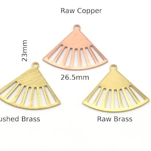 May include: Three metal fan-shaped charms in different finishes: raw copper, brushed brass, and raw brass. Each charm measures 26.5 mm wide and 23 mm high.