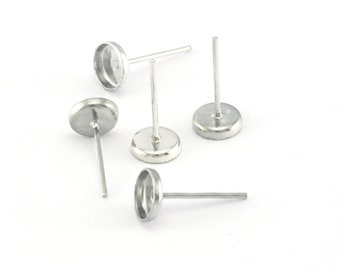 May include: Five silver earring settings with round bezels. The settings are designed to hold small cabochons or other decorative elements.