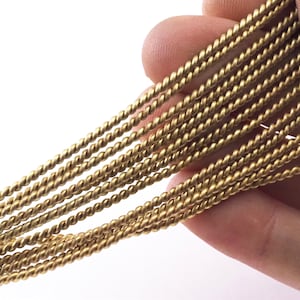 Puede incluir: Primer plano de un haz de alambre trenzado de color dorado. El alambre es liso y brillante, y está dispuesto en un patrón ordenado y paralelo.