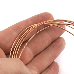 May include: Close-up of several strands of copper-colored wire, held in a hand. The wire is thin and appears to be coiled. The background is white.