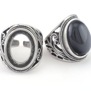 May include: Two silver rings with an ornate design. One ring has a black oval gemstone.