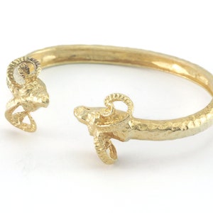 Peut inclure: Un bracelet en or avec des extrémités en tête de bélier. Le bracelet est texturé et a une finition martelée.