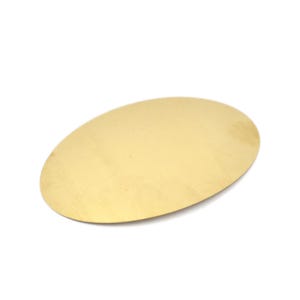 Op de afbeelding: Een glad, plat, ovaalvormig stuk van gepolijst goudkleurig metaal. Het object heeft een reflecterend oppervlak met een consistente metalen afwerking en afgeronde randen, wat een eenvoudig, onversierd en uniform uiterlijk geeft vanuit dit perspectief.