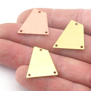 以下が含まれることがあります： ジュエリー作りのための穴が空いた三角形の金属ブランクが3つ。2つは金色、1つは銅色です。
