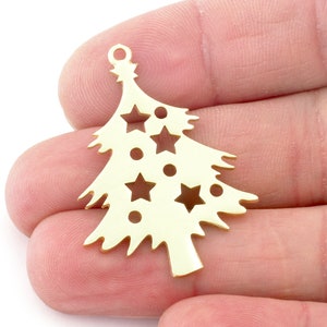 Op de afbeelding: Gouden metalen kerstboomhanger met een uitgesneden ontwerp met sterren en cirkels. De hanger heeft een lus aan de bovenkant om op te hangen.